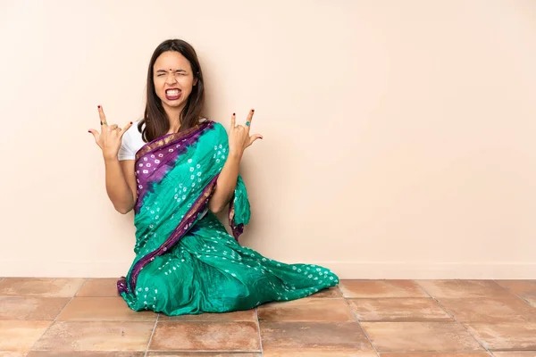 年轻的印度女人坐在地板上做号角手势 — 图库照片