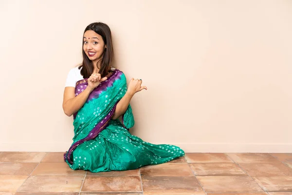Jonge Indiase Vrouw Zit Vloer Wijzend Naar Zijkant Een Product — Stockfoto