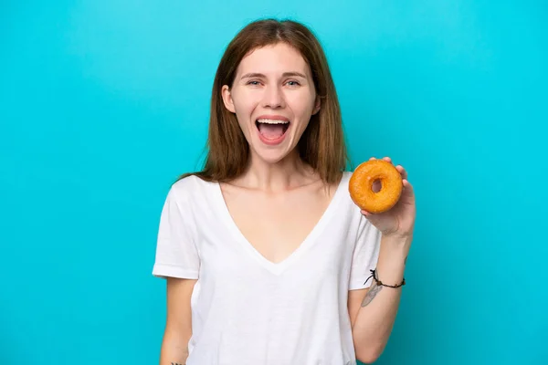 Ung Engelsk Kvinna Som Håller Munk Över Isolerad Blå Bakgrund — Stockfoto