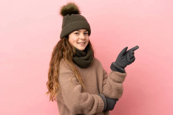 Bambina Con Cappello Invernale Isolato Sfondo Rosa Puntando Dito Verso — Foto Stock