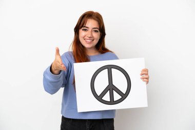 Genç kızıl saçlı kadın beyaz arka planda izole edilmiş. Elinde barış sembolü olan bir pankart var.