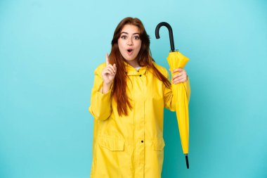 Mavi arka planda şemsiye tutan kızıl saçlı kadın çözümü fark etmek için parmağını kaldırıyor.