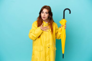 Mavi arka planda şemsiyesi olan kızıl saçlı kadın sağa bakarken şaşırmış ve şok olmuştu.