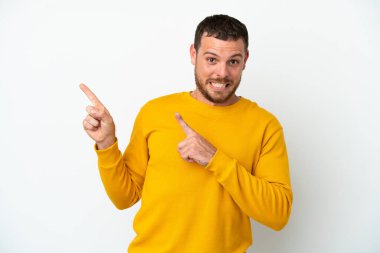 Beyaz arka planda izole edilmiş genç Brezilyalı adam korkmuş ve kenarı işaret ediyor.