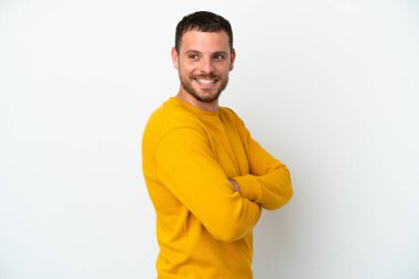 Genç Brezilyalı bir adam beyaz arka planda izole edilmiş, yana bakıyor ve gülümsüyor.