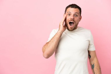 Pembe arka planda mahsur kalmış Brezilyalı genç adam şaşırmış ve şok olmuş bir yüz ifadesiyle