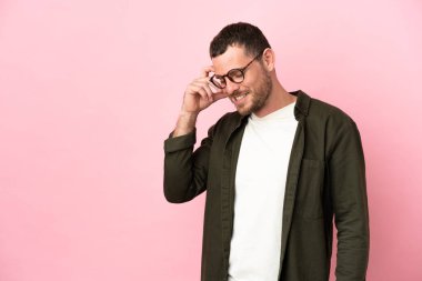 Genç Brezilyalı adam pembe arka planda izole edilmiş gülüyor.
