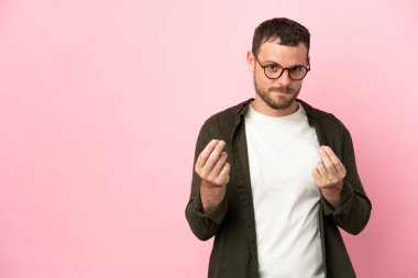 Pembe arka planda izole edilmiş genç Brezilyalı adam para hareketi yapıyor ama mahvoldu.