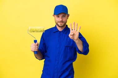 Ressam Brezilyalı adam sarı arka planda izole edilmiş mutlu ve parmaklarıyla dört tane sayıyor.