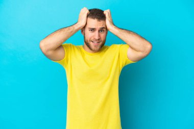 Mavi arka planda izole edilmiş yakışıklı beyaz adam gergin hareketler yapıyor.