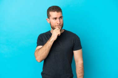 Mavi arka planda soyutlanmış yakışıklı, beyaz bir adam. Şüpheleri ve düşünceleri var.