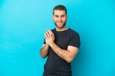 Genç yakışıklı beyaz adam, mavi arka planda izole edilmiş bir şekilde bir şeyler planlıyor.