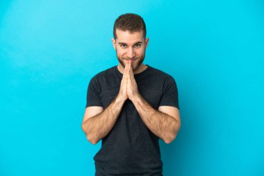 Mavi arka planda izole edilmiş yakışıklı beyaz adam avuç içlerini bir arada tutuyor. İnsan bir şey ister.