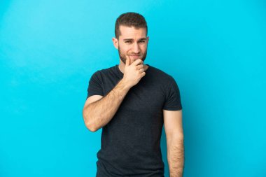 Mavi arka planda izole edilmiş yakışıklı beyaz adam kuşkuları var.