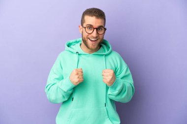 Mor arka planda izole edilmiş yakışıklı beyaz adam galibiyeti kutluyor.