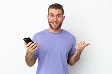 Beyaz arka planda izole edilmiş genç, yakışıklı beyaz bir adam cep telefonu kullanıyor.