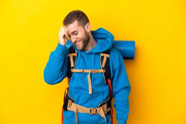 Sarı arka planda izole edilmiş büyük sırt çantalı beyaz bir dağcı.