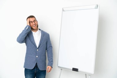 Beyaz arka planda izole edilmiş beyaz panoda sunum yapan genç iş kadını çok gülümsüyor.