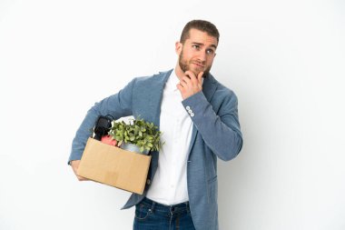 Beyaz arka planda izole edilmiş eşyalarla dolu bir kutuyu alıp yukarı bakarken genç beyaz bir adam hamle yapıyor.