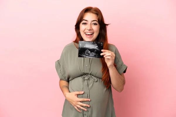 若いですRedhead Caucasian女性隔離上のピンクの背景妊娠と驚きを保持しながら超音波 — ストック写真
