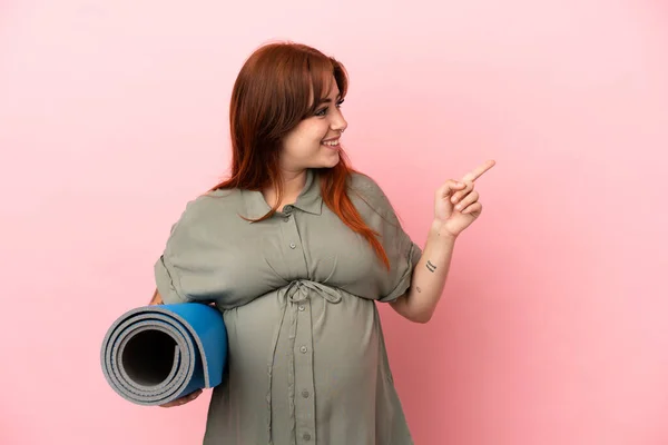 Young Redhead Caucasian Woman Isolated Pink Background Pregnant Holding Mat — Stockfoto