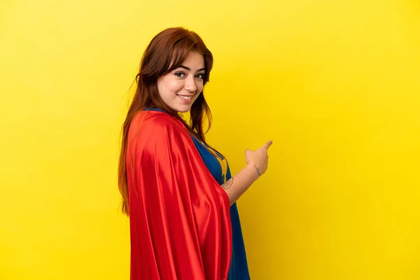 Super Hero Redhead Woman Isolated Yellow Background Pointing Back — Stock fotografie