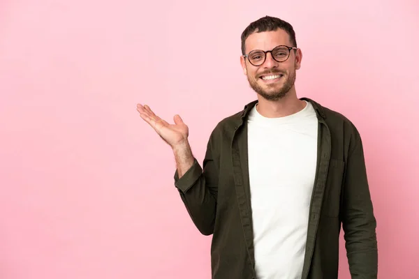 Jovem Brasileiro Isolado Fundo Rosa Segurando Copyspace Imaginário Palma Mão — Fotografia de Stock