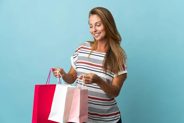 青の背景に隔離された中世のブラジル人女性ショッピングバッグを保持し それの中を見て — ストック写真