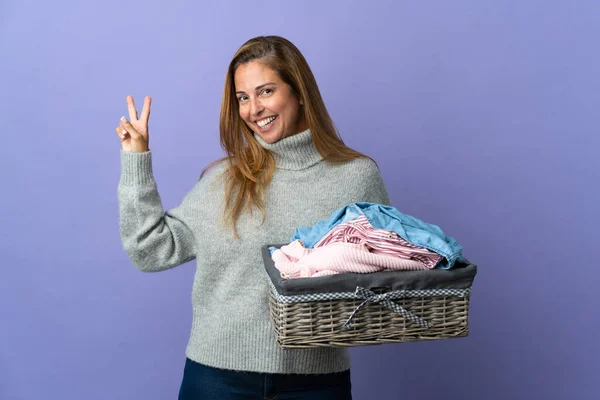 Frau Mittleren Alters Hält Einen Wäschekorb Auf Violettem Hintergrund Und — Stockfoto
