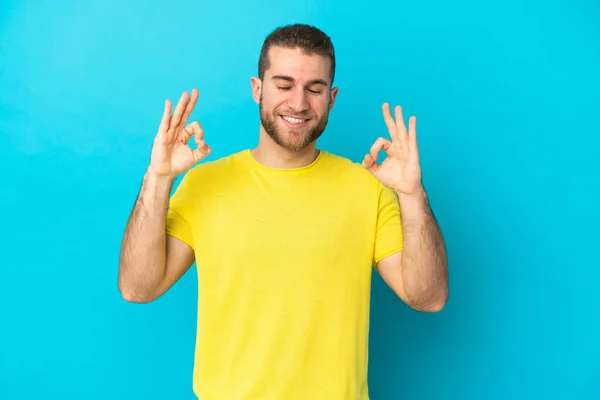 Jonge Knappe Blanke Man Geïsoleerd Blauwe Achtergrond Zen Pose — Stockfoto