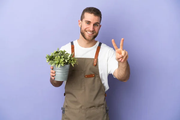 Jardineiro Caucasiano Homem Segurando Uma Planta Isolada Fundo Amarelo Sorrindo — Fotografia de Stock