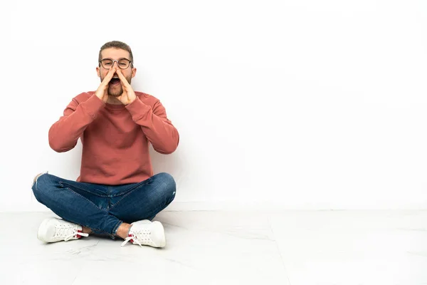 Young Handsome Man Sitting Floor Shouting Announcing Something — Zdjęcie stockowe