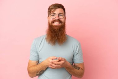 Kırmızımsı beyaz adam pembe arka planda izole edilmiş gülüyor.