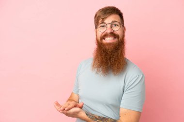 Pembe arka planda izole edilmiş genç beyaz adam alkışlıyor.