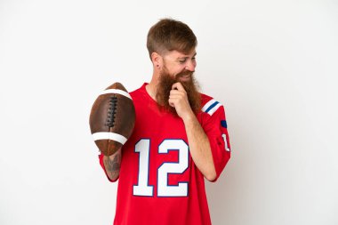 Beyaz arka planda ragbi oynayan beyaz tenli genç, beyaz bir adam yan tarafa bakıyor ve gülümsüyor.