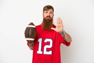 Beyaz arka planda ragbi oynayan Kafkasyalı genç adam dur hareketi yapıyor.