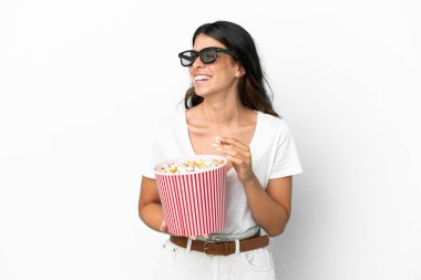 Beyaz arka planda 3 boyutlu gözlüklü ve elinde koca bir kova patlamış mısır tutan beyaz tenli bir kadın.