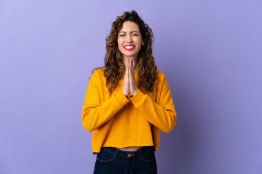 Mor arka planda izole edilmiş genç beyaz kadın avuç içlerini bir arada tutuyor. İnsan bir şey ister.