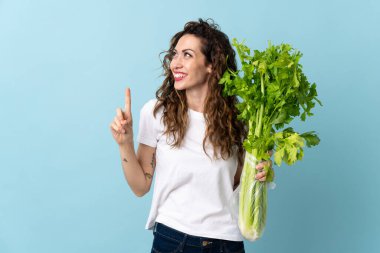Mavi arka planda izole edilmiş bir kereviz tutan genç kadın çözümü fark etmek için parmağını kaldırıyor.