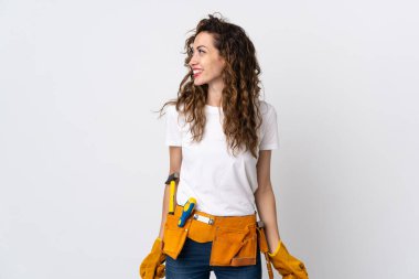 Beyaz arka planda izole edilmiş genç elektrikçi yan tarafa bakıyor ve gülümsüyor.