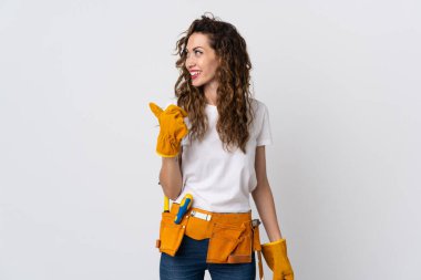 Beyaz arka planda izole edilmiş genç elektrikçi bir ürünü sunmak için kenarı işaret ediyor.