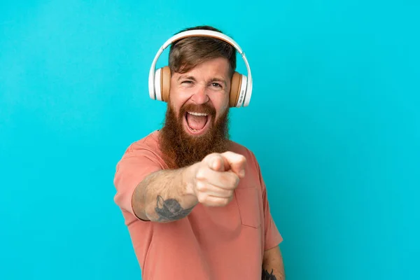 Young Reddish Caucasian Man Isolated Blue Background Listening Music Pointing — Fotografia de Stock
