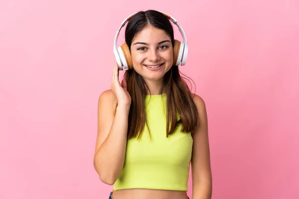 若いですCaucasian女性隔離上のピンクの背景リスニング音楽 — ストック写真