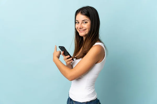 Молода Біла Жінка Використовує Мобільний Телефон Ізольовано Синьому Фоні Вказуючи — стокове фото