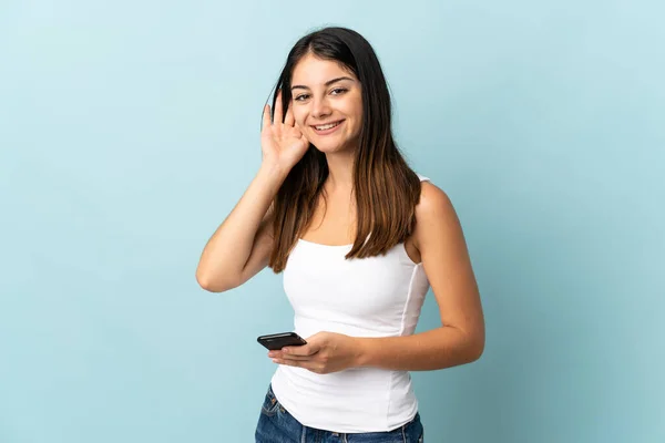 Mujer Caucásica Joven Usando Teléfono Móvil Aislado Fondo Azul Escuchando —  Fotos de Stock