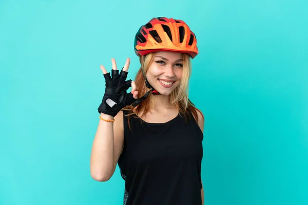Młoda Rowerzysta Dziewczyna Odizolowanym Niebieskim Tle Pokazuje Znak Palcami — Zdjęcie stockowe