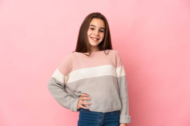 Küçük kız pembe arka planda gülüyor.