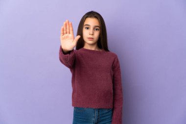 Mor arka planda izole edilmiş küçük bir kız durdurma hareketi yapıyor