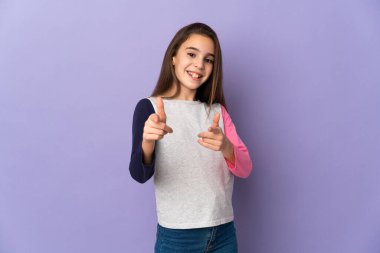 Mor arka planda izole edilmiş küçük bir kız öne bakıyor ve gülümsüyor.