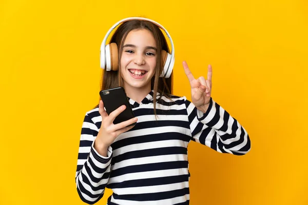 Κοριτσάκι Απομονωμένο Κίτρινο Φόντο Ακούγοντας Μουσική Μια Κινητή Ροκ Χειρονομία — Φωτογραφία Αρχείου